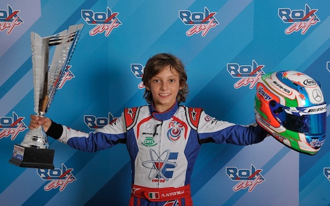 A young Kimi Antonelli holding a trophy and his Mercedes-AMG helmet after winning the Rok Mini class in 2018