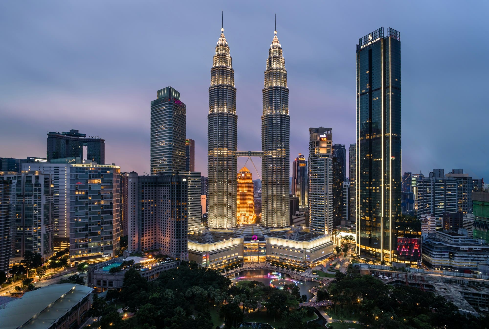 The Petronas Towers lit up at dusk above KLCC Park in Kuala Lumpur, Malaysia