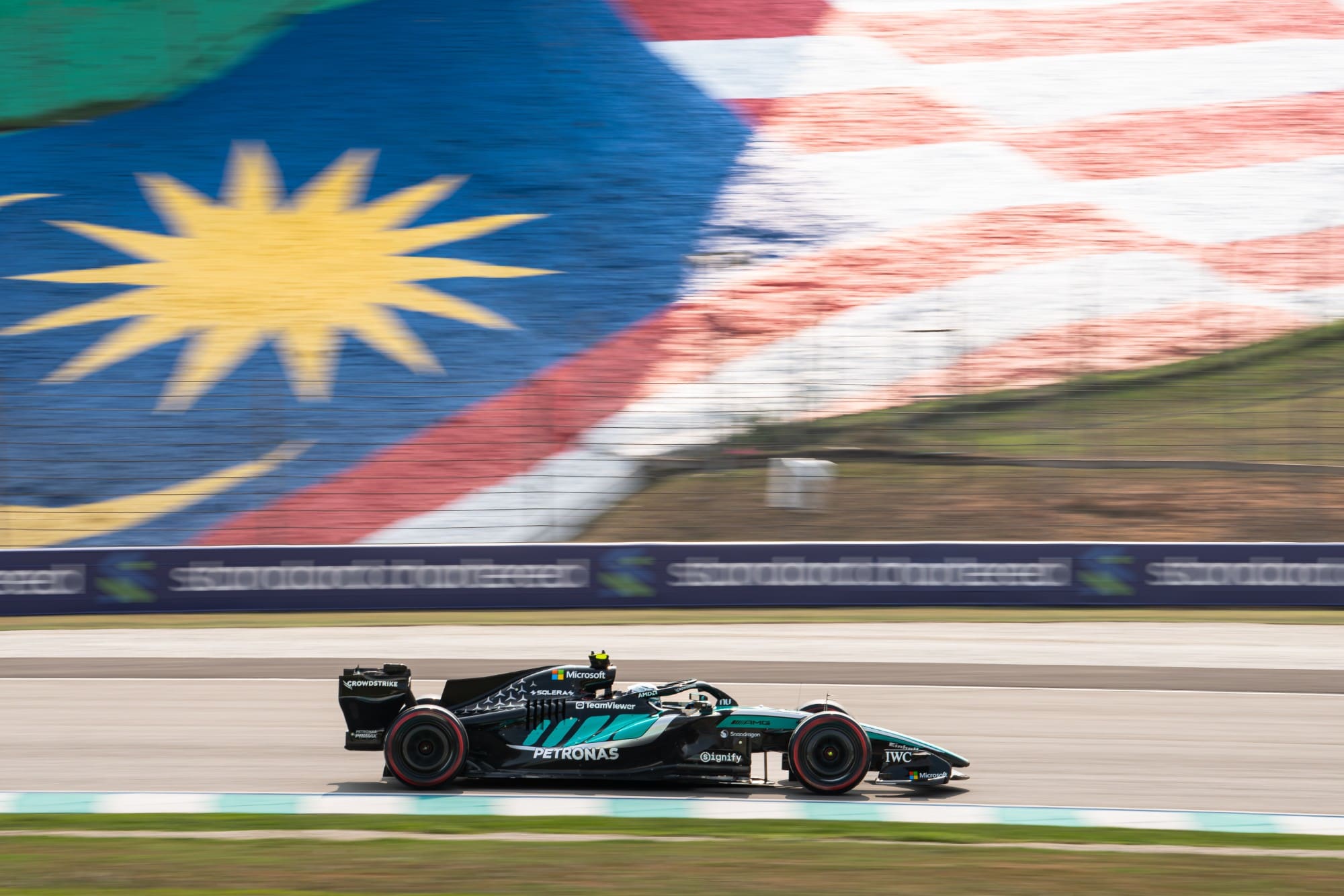 A Mercedes speeds past the giant Malaysian flag painted on the hillside at Sepang