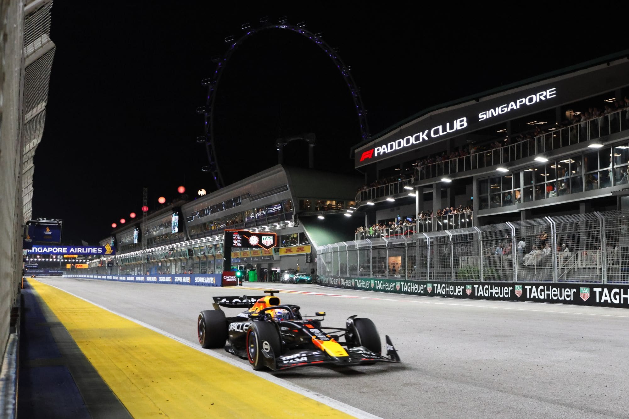 Max Verstappen drives his Red Bull along the pit straight past the illuminated Singapore Flyer and Paddock Club at the 2025 Singapore Grand Prix