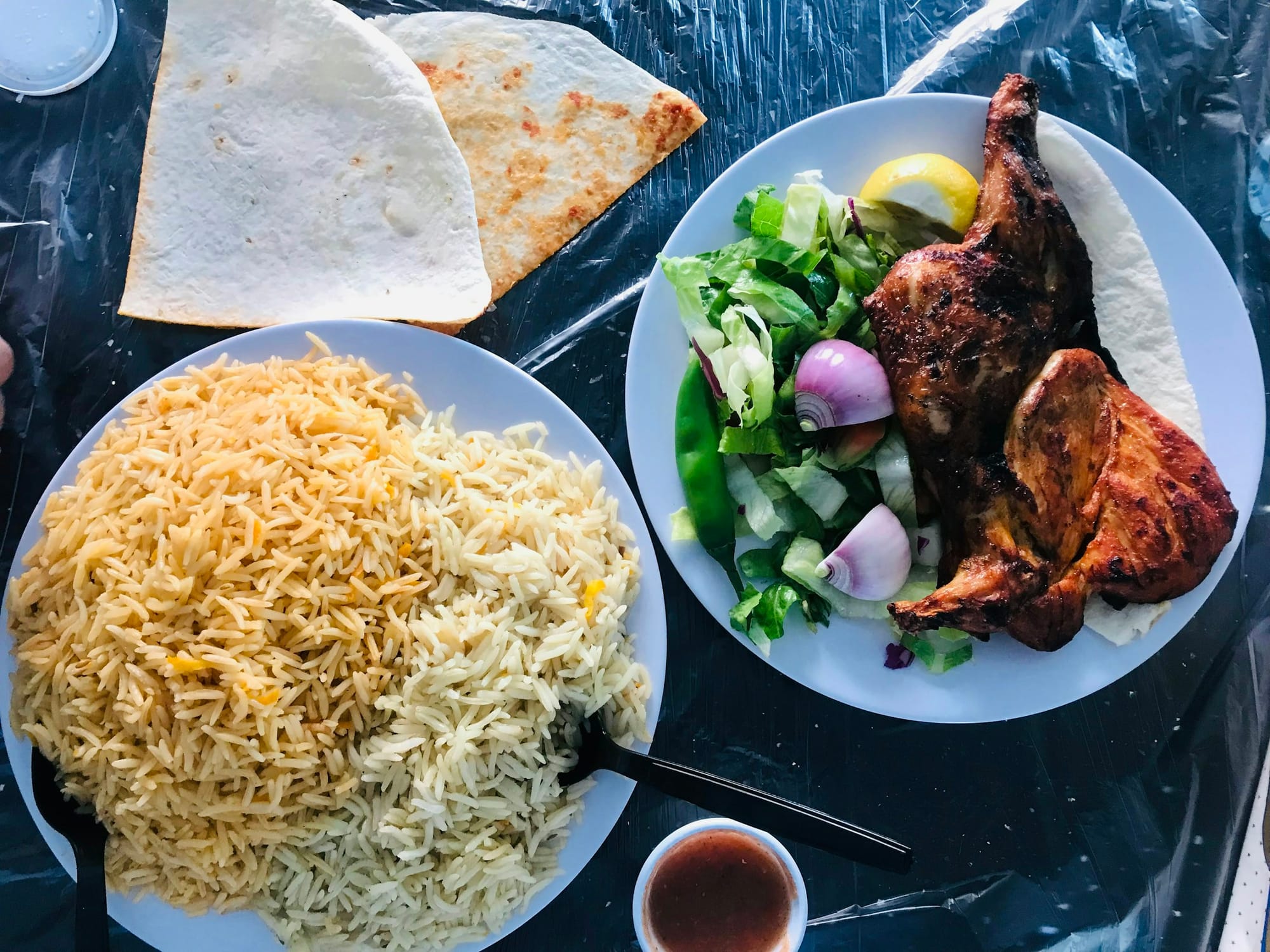 Plates of roast chicken, spiced rice, salad and flatbread