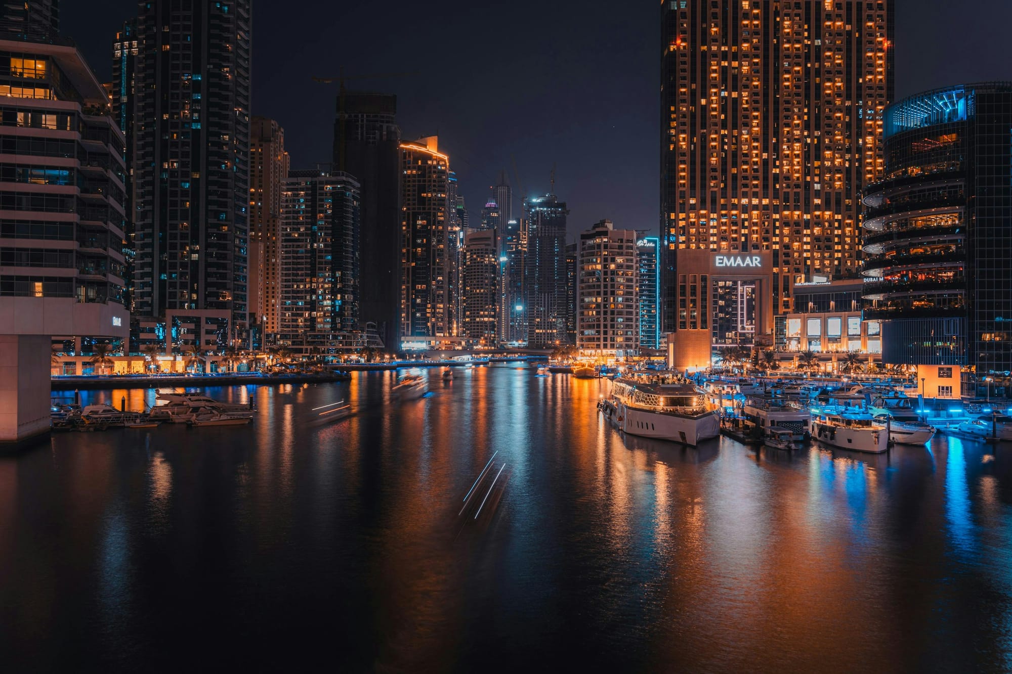 Dubai Marina lit up at night, with boats on the water