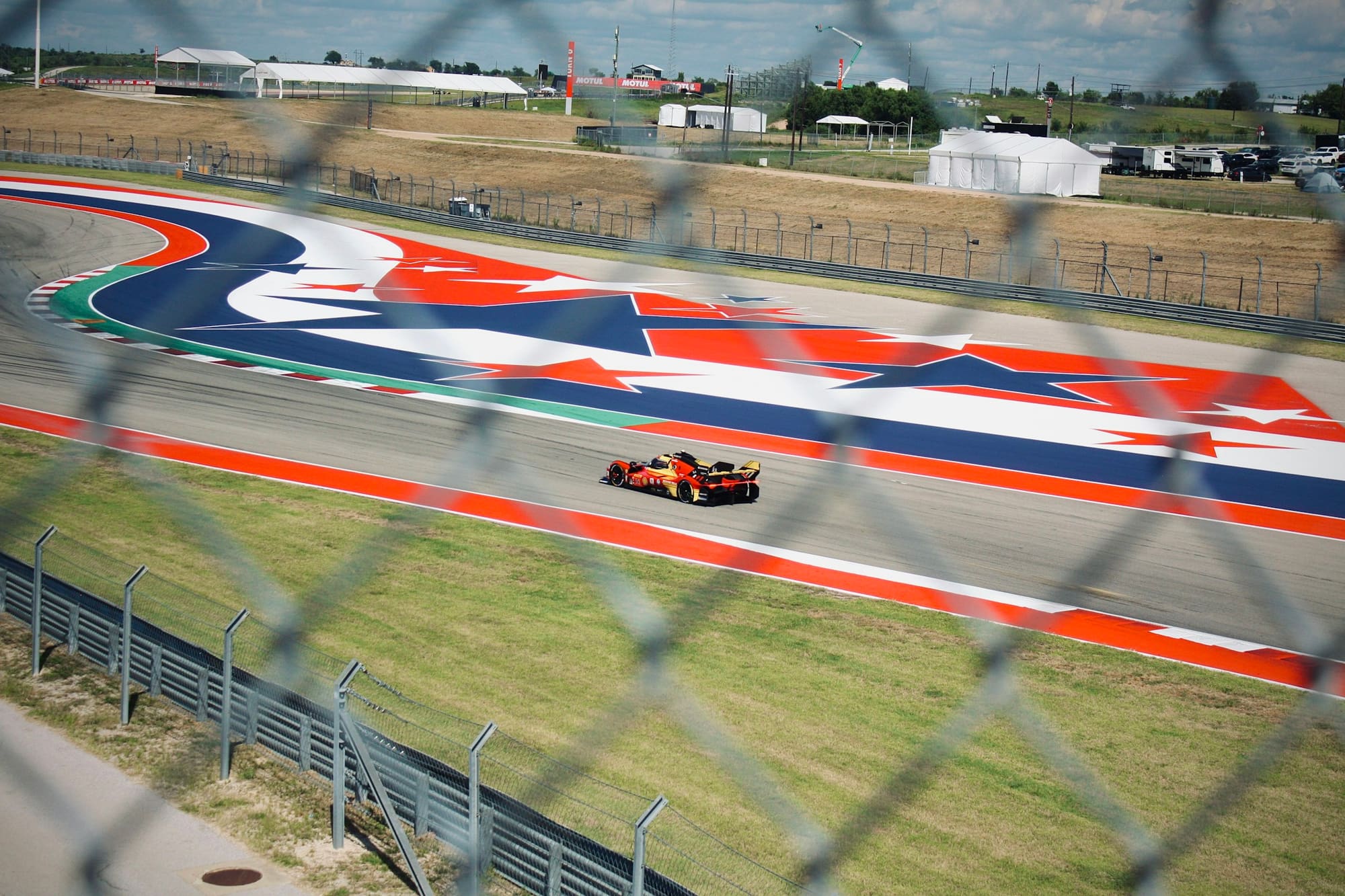 A Ferrari Hypercar on the red, white and blue kerbs at Circuit of the Americas during the Lone Star Le Mans